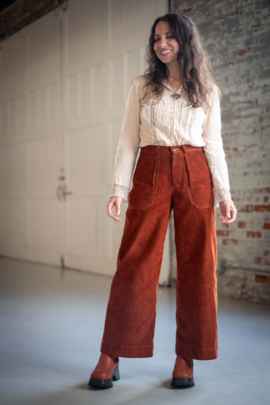 Woman wearing the Pinyon Pants sewing pattern from Sew Liberated on The Fold Line. A pants pattern made in denim, twill, or canvas fabric, featuring a fitted waistband, zip fly, wide leg, and patch pockets. 