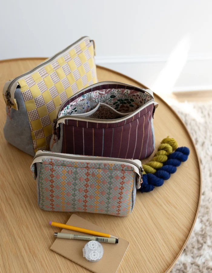 The Plover Pouch sewing pattern from Noodlehead on The Fold Line. A bag pattern made in quilting cotton or cotton/linen blend fabric, featuring three sizes, a dividable interior pocket, zipper top, and metal snap detail.