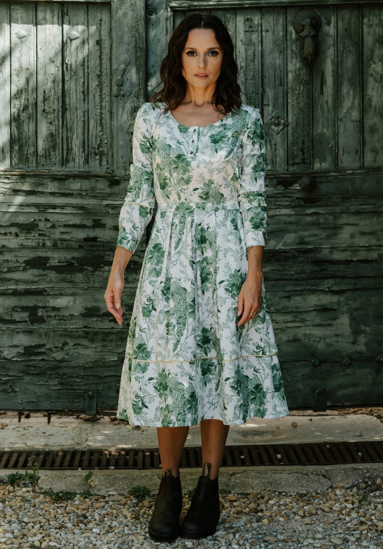 Woman wearing the Prose Dress sewing pattern from Maison Fauve on The Fold Line. A dress pattern made in poplin, crepe, lightweight jacquard, twill, dupion, viscose, cotton, linen, tencel, or silk fabric, featuring a scoop neckline with a button placket, long sleeves, pleated skirt, elasticated back waistband, side pockets, and midi length.