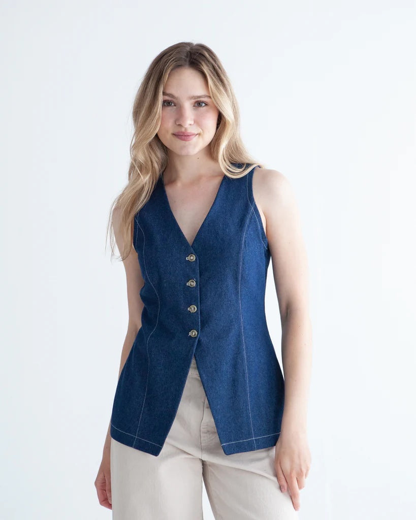 Woman wearing the Quinn Vest sewing pattern from True Bias on The Fold Line. A sleeveless top pattern made in linen, cotton twill, corduroy, or denim fabric, featuring a V-neckline, princess seams, centre front button opening, back buckle, and hip length.