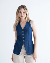 Woman wearing the Quinn Vest sewing pattern from True Bias on The Fold Line. A sleeveless top pattern made in linen, cotton twill, corduroy, or denim fabric, featuring a V-neckline, princess seams, centre front button opening, back buckle, and hip length.