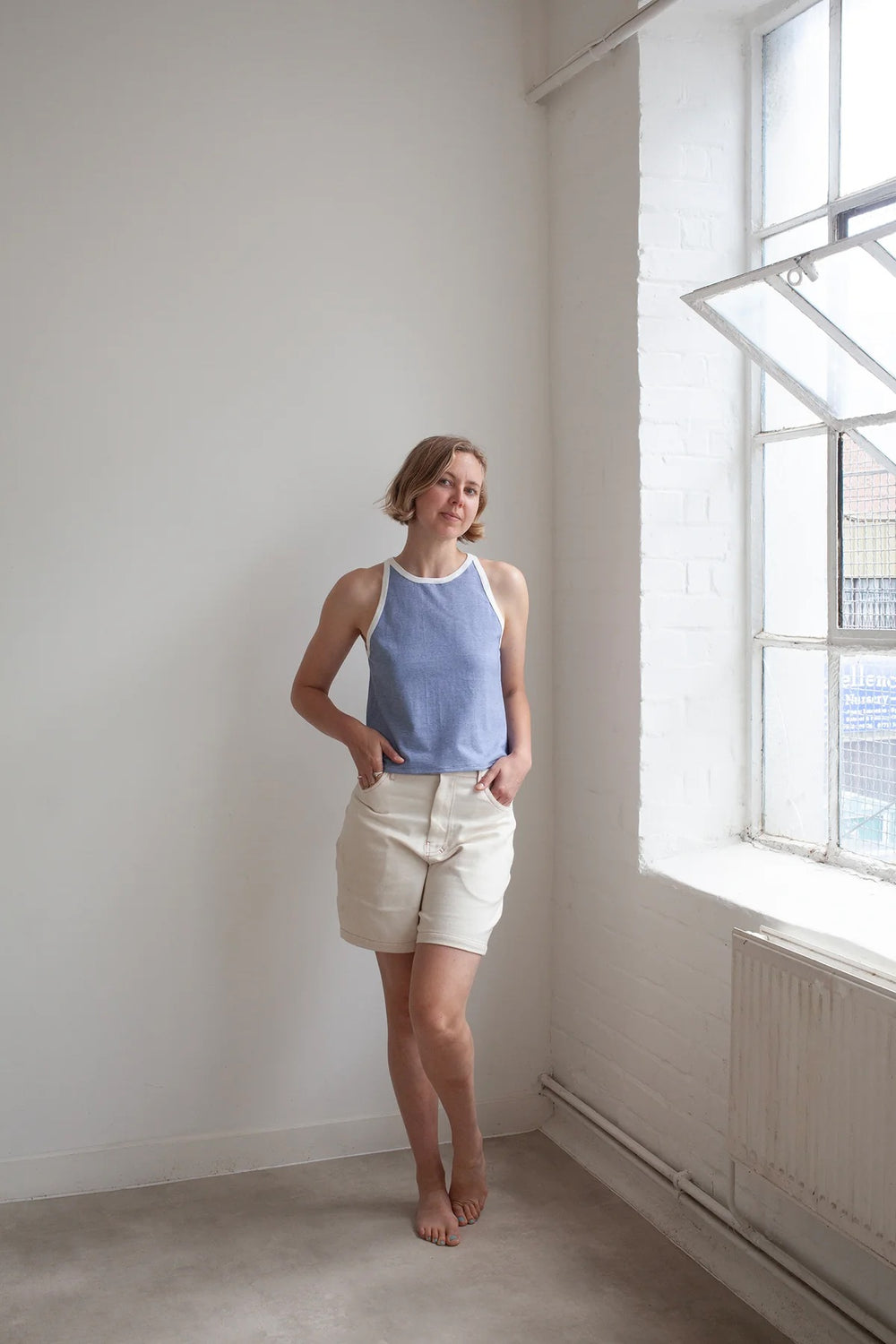 Woman wearing the Racer Vest sewing pattern from The Modern Sewing Co. on The Fold Line. A tank top pattern made in cotton jersey, bamboo jersey, modal knit, or pointelle jersey fabric, featuring a high round neckline, narrow shoulder, low scoop under the arm, and contrast binding.