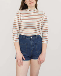 Woman wearing the Ramona Top sewing pattern from Oh Me Oh My Sewing on The Fold Line. A top pattern made in knit fabric, featuring a mock neck and 3/4 length sleeves. 