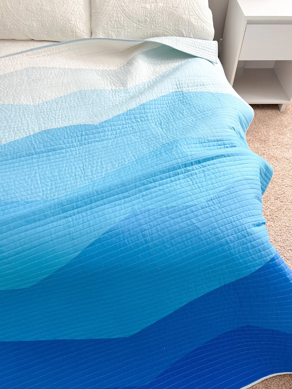 The Ranges Quilt sewing pattern from Modern Handcraft on The Fold Line. A quilt pattern made in quilting cotton fabric, featuring jagged bands of blue arranged from light to dark.