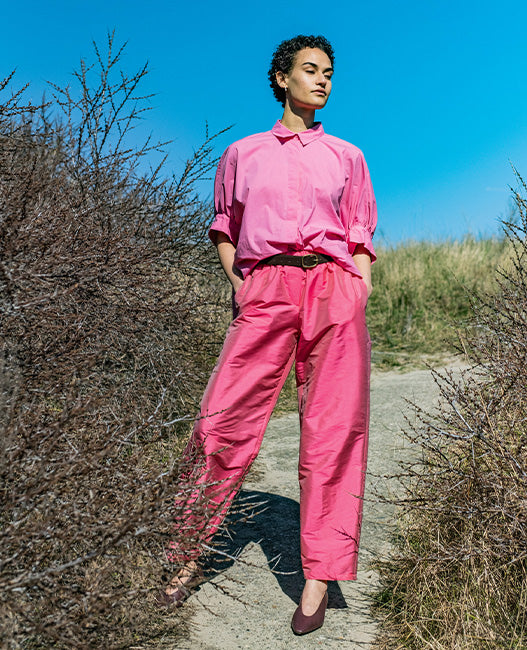 Woman wearing the Raven Trousers sewing pattern from Fibre Mood on The Fold Line. A pants pattern made in poplin, gabardine, cotton twill, nylon, seersucker, linen, corduroy, satin, ripstop, or viscose crepe fabric, featuring a relaxed fit, elastic waist, and pockets.