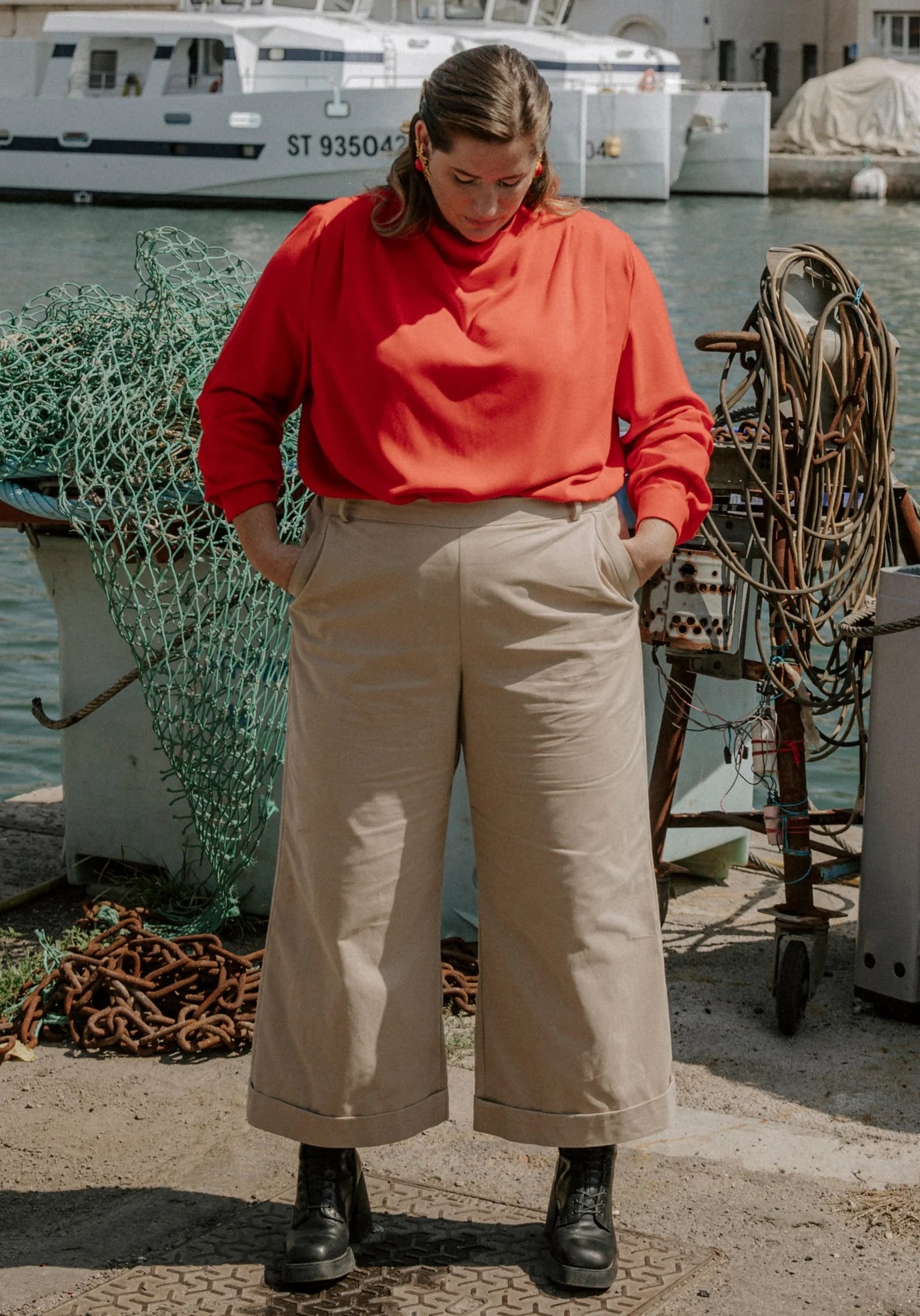 Woman wearing the Récif Trousers sewing pattern from Maison Fauve on The Fold Line. A trousers pattern made in cotton gabardine, denim, cotton satin, soft jacquard, or lightweight wool fabric, featuring a mid-rise waist, waistband, fitted hips, slant pockets, invisible side zip, and cropped wide leg with a cuff. 