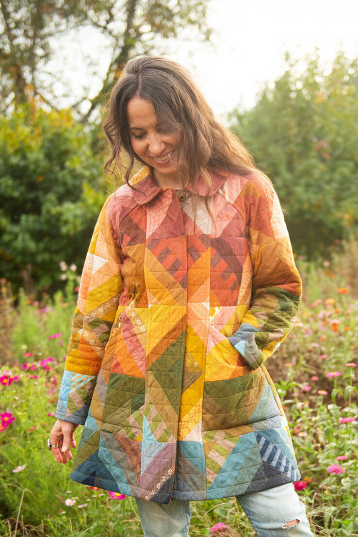 Woman wearing the Retazo Coat sewing pattern from Sew Liberated on The Fold Line. A quilted coat pattern made in cotton-linen blend, linen, quilting cotton, shirting, rayon challis, or ikat handloom cotton fabric, featuring a curved collar, princess seams, two-piece raglan sleeves, and deep pockets.