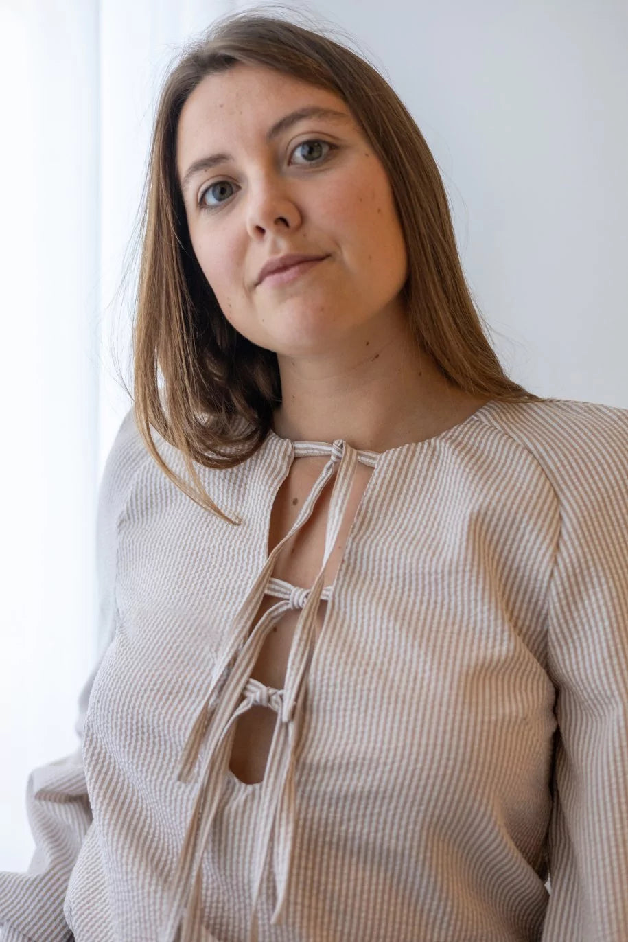 Woman wearing the Reya Top sewing pattern from Fibre Mood on The Fold Line. A top pattern made in viscose, lightweight lyocell or cupro, crêpe, silk or satin fabric, featuring a deep V-neckline with ties and long raglan sleeves.