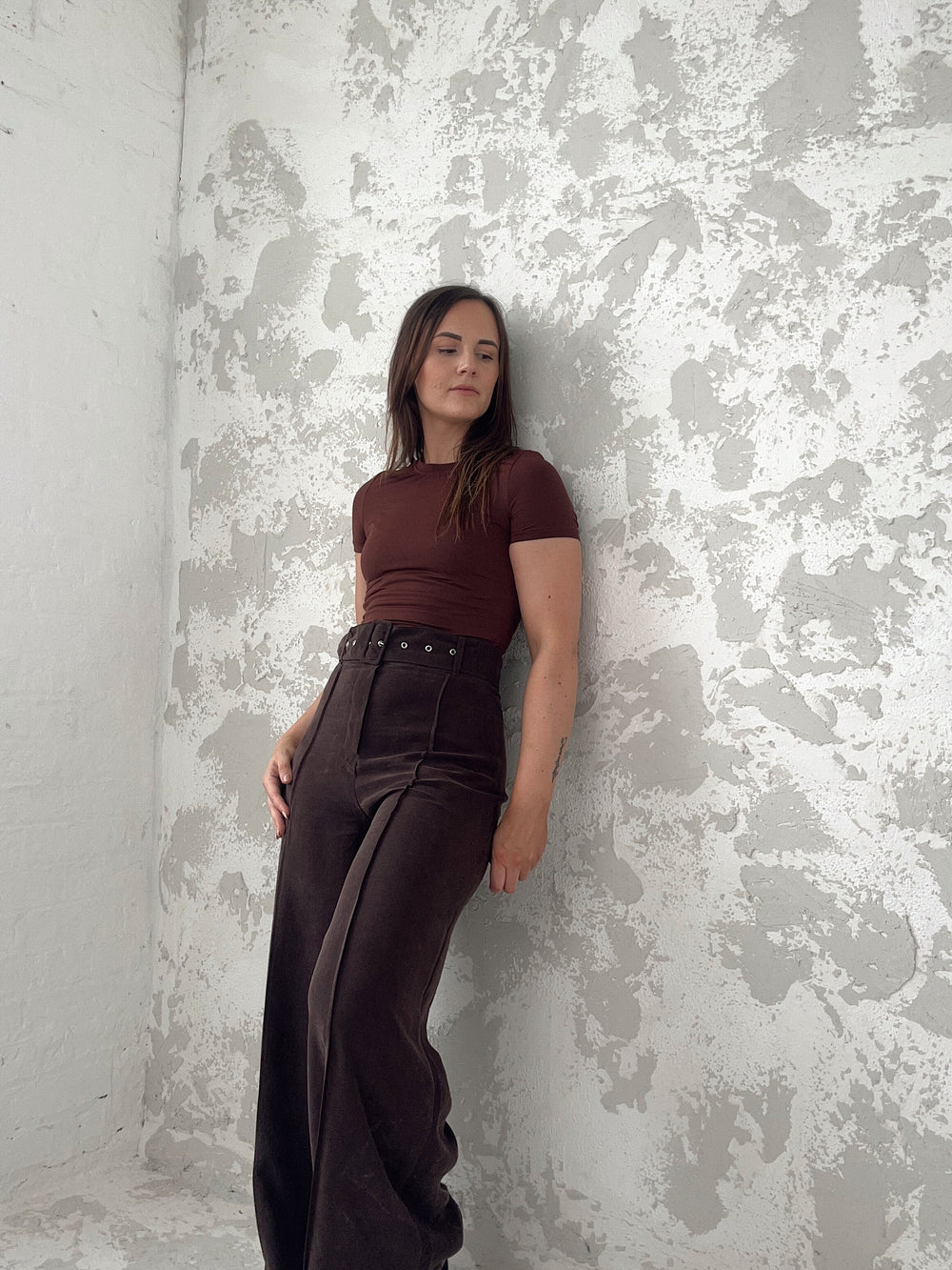Woman wearing the Riviera Trousers sewing pattern from NH Patterns on The Fold Line. A trousers pattern made in modal, tencel, or suiting fabric, featuring a wide waistband, belt, fly front, pintuck detail, and wide legs.