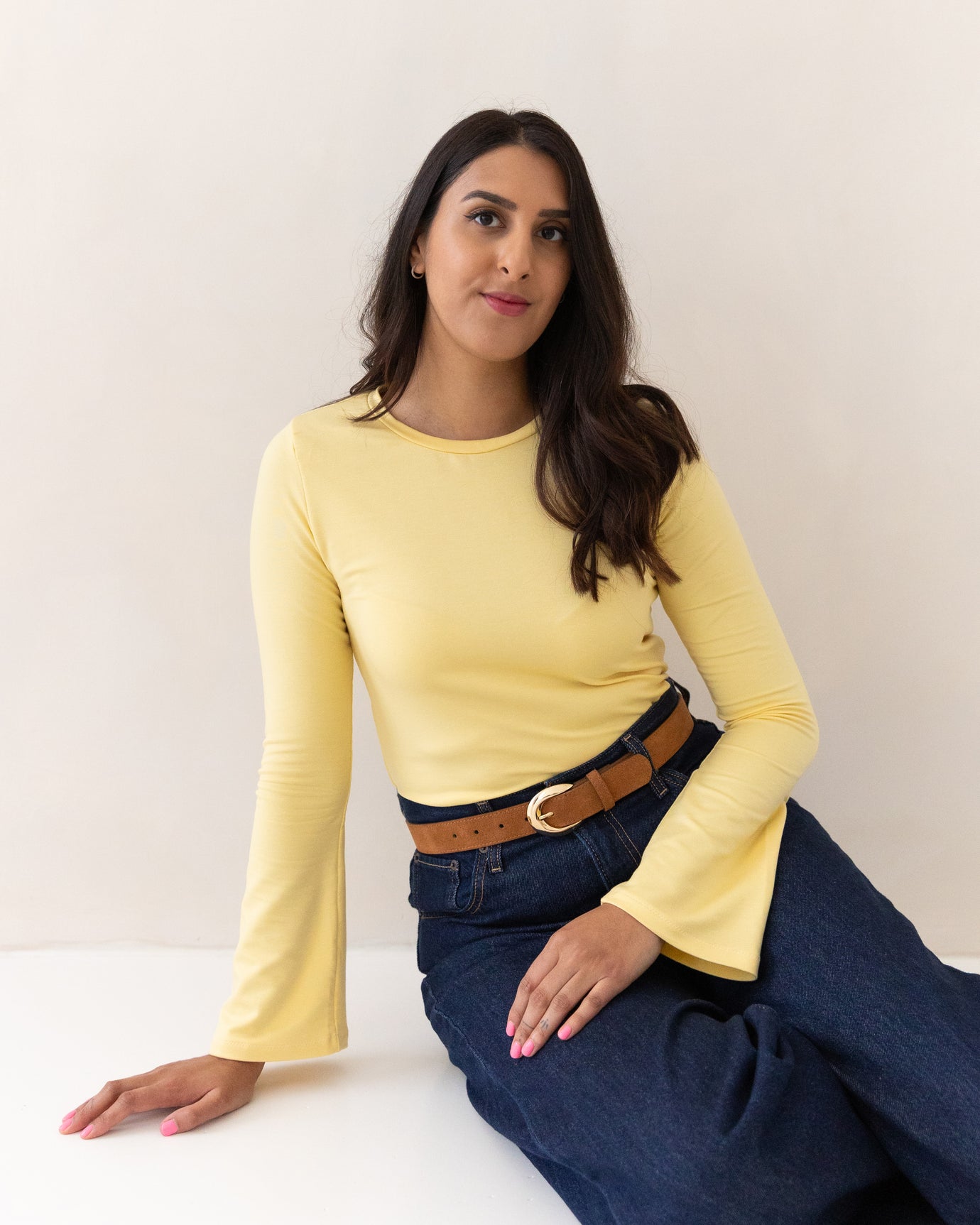 Woman wearing the Romy Top sewing pattern from Tammy Handmade on The Fold Line. A top pattern made in knit fabric, featuring a round neckline and flared long sleeves.
