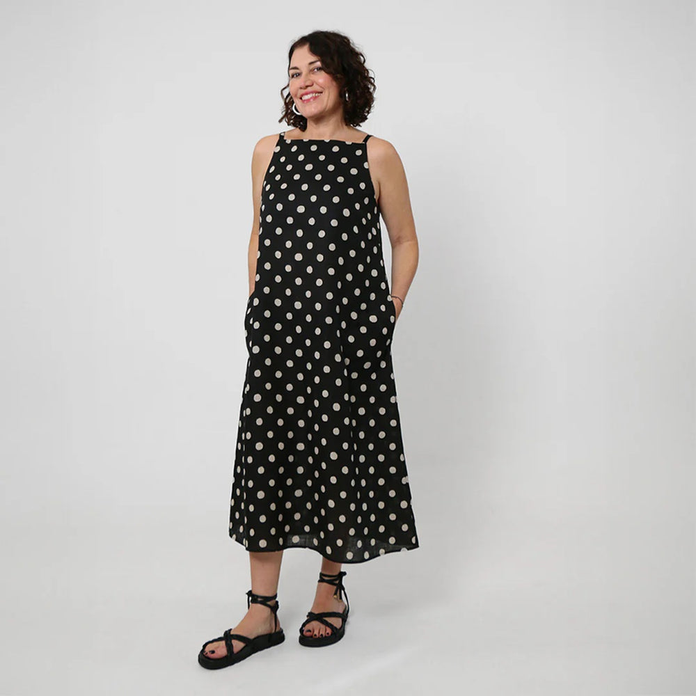 Woman wearing the Romy Dress sewing pattern from Tessuti Fabrics on The Fold Line. A sleeveless dress pattern made in linen, cotton, silk, rayon, or viscose fabric, featuring a semi-fitted silhouette, square neckline, shoulder straps, in-seam pockets, and midi length.