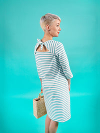 Woman wearing the Romy Dress sewing pattern from Tilly and the Buttons on The Fold Line. A dress pattern made in knit fabric, featuring a slash envelope neckline with back ties, three quarter sleeves, and knee length.