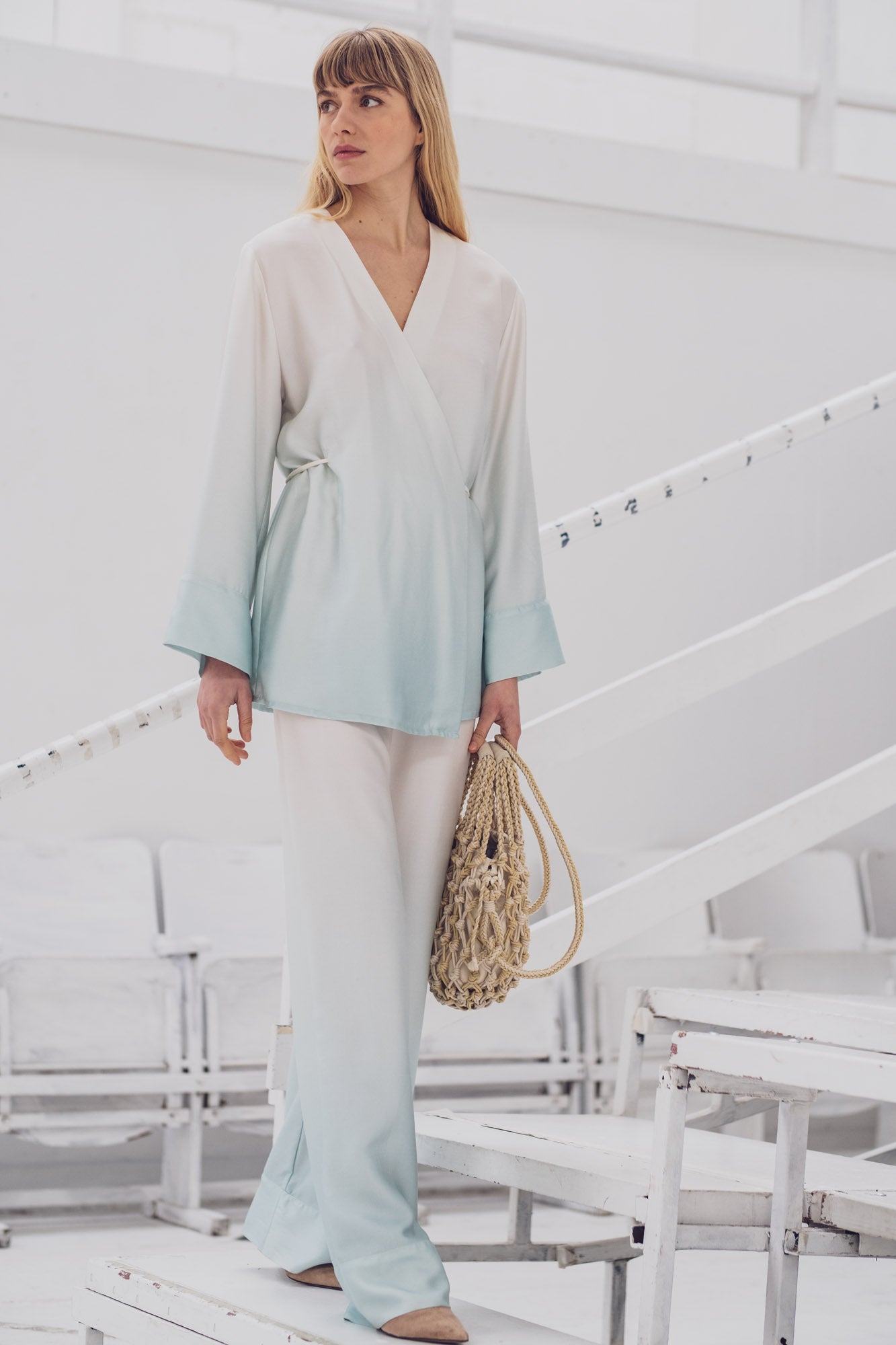 Woman wearing the Ronya Blouse sewing pattern from Fibre Mood on The Fold Line. A wrap top pattern made in lyocell twill, satin, acetate, lurex, charmeuse, silk, or crepe de chine fabric, featuring a relaxed fit, V-neckline, long sleeves, and ties.