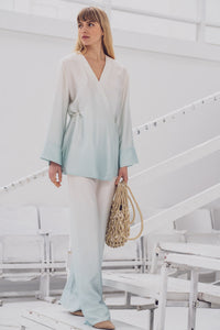 Woman wearing the Ronya Blouse sewing pattern from Fibre Mood on The Fold Line. A wrap top pattern made in lyocell twill, satin, acetate, lurex, charmeuse, silk, or crepe de chine fabric, featuring a relaxed fit, V-neckline, long sleeves, and ties.