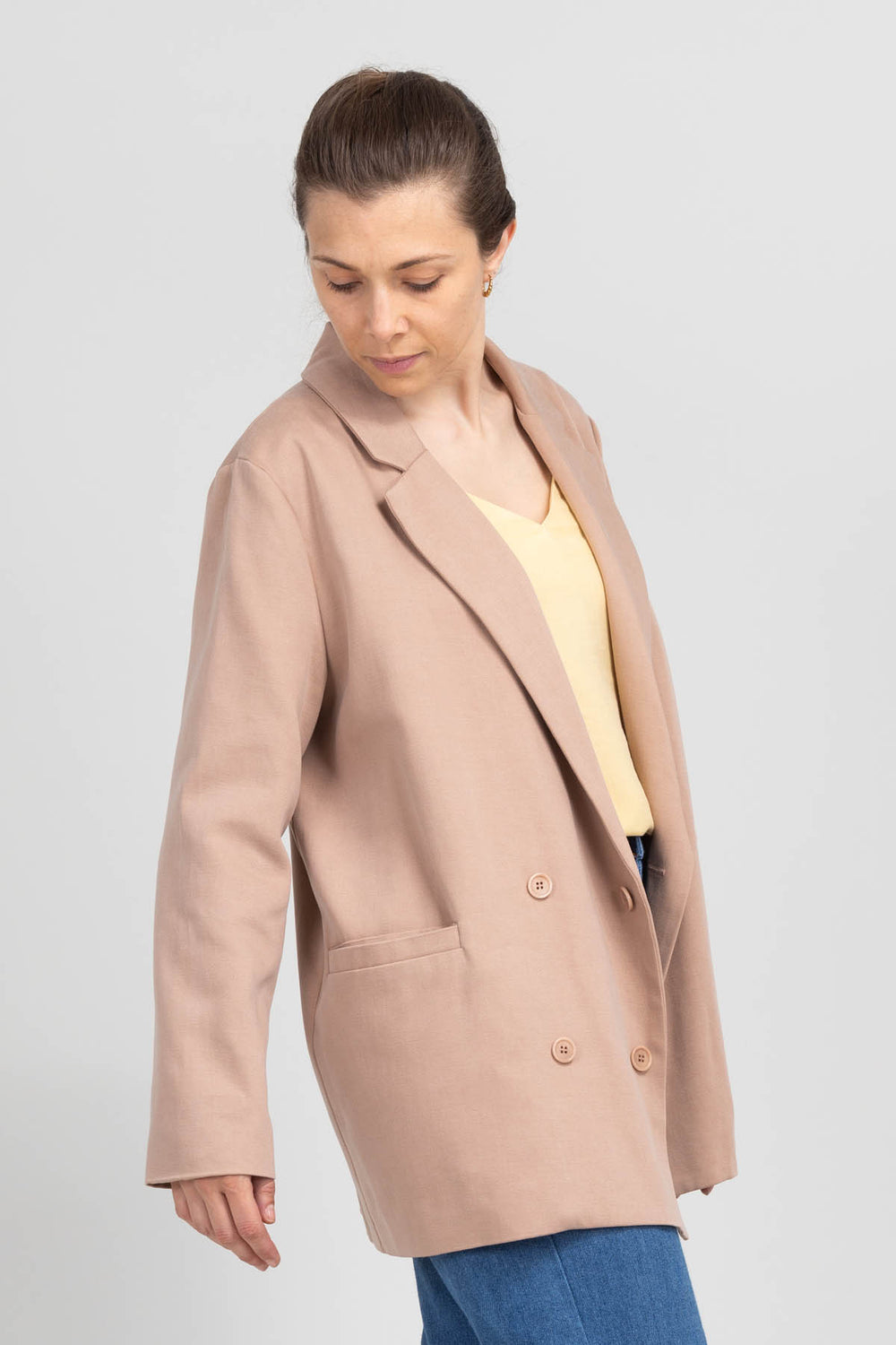 Woman wearing the Rose Blazer sewing pattern from I AM Patterns on The Fold Line. A lined blazer pattern made in lightweight tweed, lightweight wool, viscose or cotton twill, heavyweight crepe, or gabardine fabric, featuring an oversized silhouette, double-breasted front, lapel collar, and welt pockets.