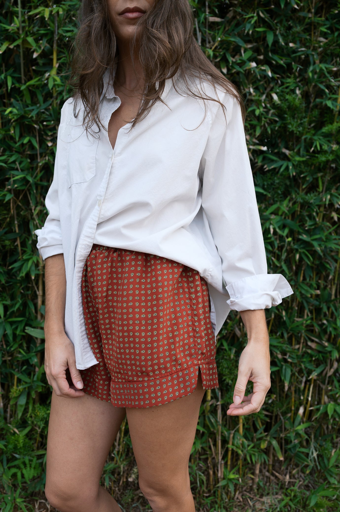 Woman wearing the Rose Bottoms sewing pattern from Paradise Patterns on The Fold Line. A shorts pattern made in cotton or linen fabric, featuring an elastic high waist, back patch pocket, and hem band with a V-cutout.