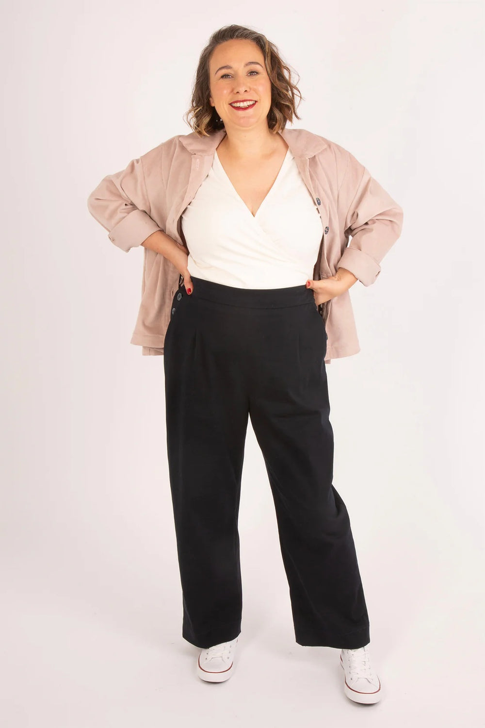 Woman wearing the Rosemary Trousers sewing pattern from Sew Over It on The Fold Line. A trousers pattern made in cotton twill, stretch cotton, denim, or canvas fabric, featuring waist darts at the front and back, a flat front waistband and elasticated back waistband, side button opening, slanted pockets at the front, and patch pockets at the back.