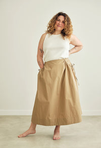 Woman wearing the Rowan Skirt sewing pattern from the Modern Sewing Co. on The Fold Line. A skirt pattern made in cotton lawn, poplin, seersucker, linen, cotton twill, lightweight wool or wool blends, or tencel fabric, featuring an A-line silhouette, gathered side pocket openings, deep hem facing, and midi length.