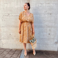 Woman wearing the Rumi Dress sewing pattern from Sew.lala Patterns on The Fold Line. A dress pattern made in linen, poplin, viscose, or silk fabric, featuring a relaxed fit, deep V neck, dropped shoulders, short sleeves, elasticated waist, and knee length.