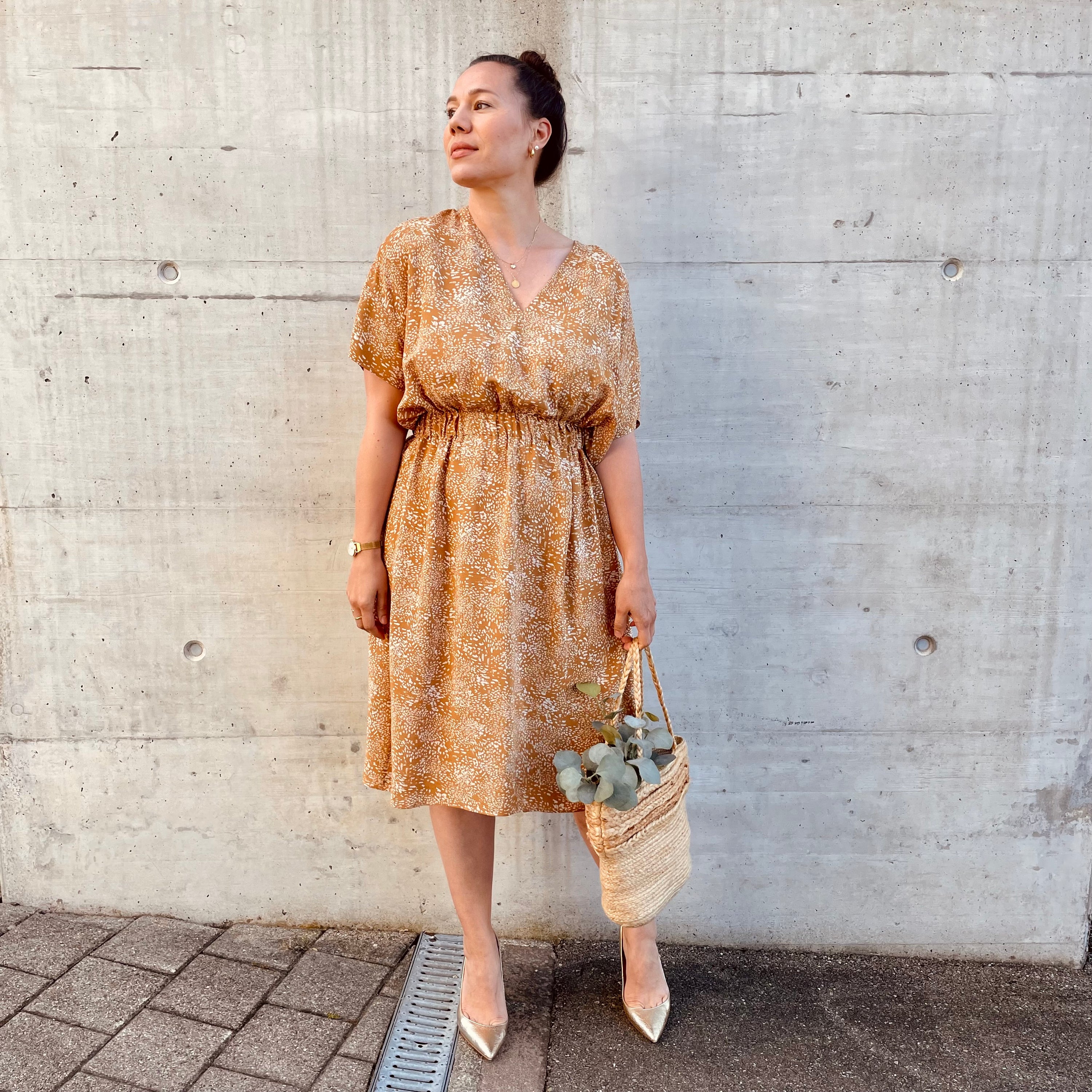 Woman wearing the Rumi Dress sewing pattern from Sew.lala Patterns on The Fold Line. A dress pattern made in linen, poplin, viscose, or silk fabric, featuring a relaxed fit, deep V neck, dropped shoulders, short sleeves, elasticated waist, and knee length.