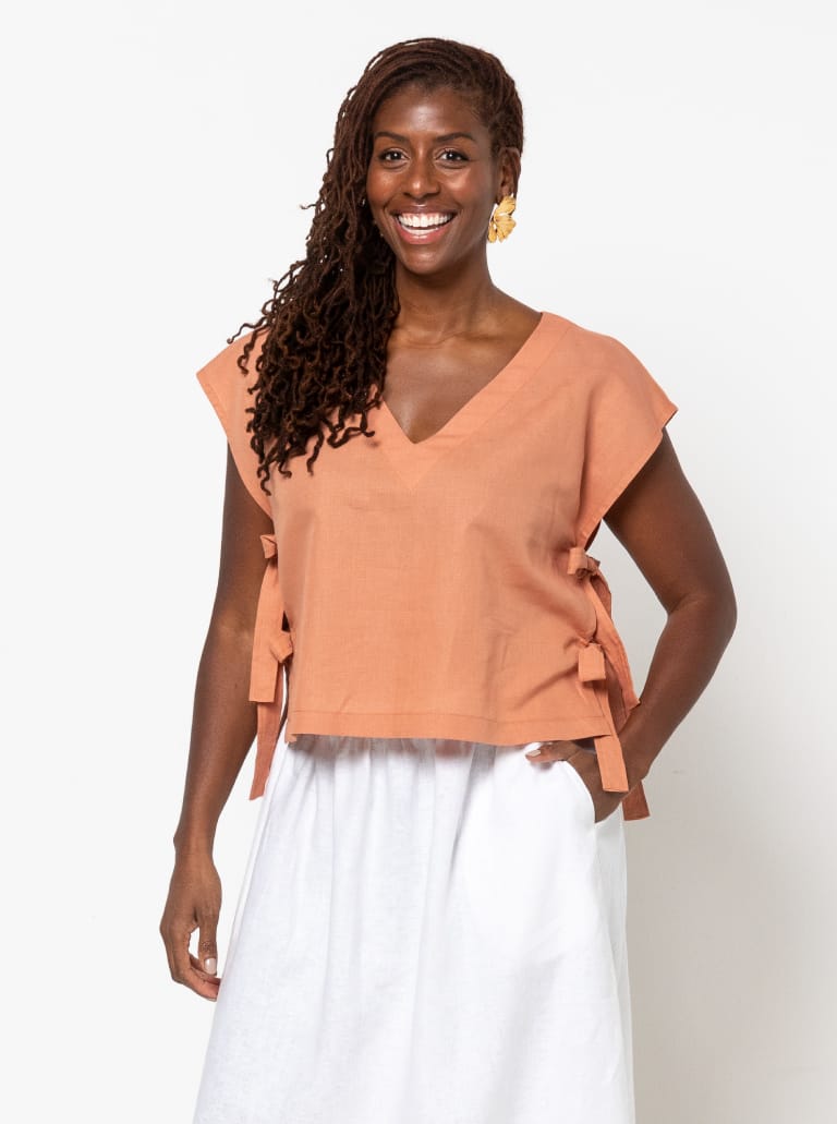 Woman wearing the Rumi Woven Top sewing pattern from Style Arc on The Fold Line. A top pattern made in denim, cotton duck, cheesecloth, or cotton voile fabric, featuring a V-neck and open side seams with ties.