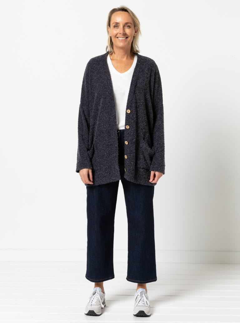 Woman wearing the Sabel Boyfriend Knit Cardi sewing pattern from Style Arc on The Fold Line. A cardigan pattern made in sweater knit fabric, featuring an oversized fit, dropped armhole, slim sleeve, patch pockets, and large buttons.