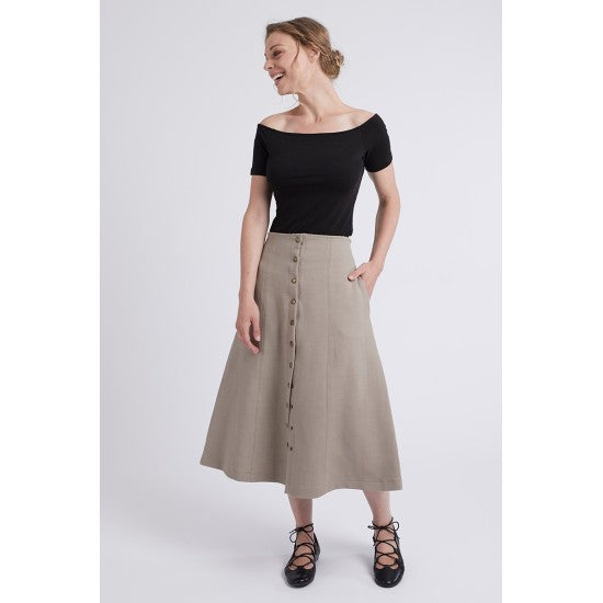 Woman wearing the Sabine Skirt sewing pattern from Coralie Bijasson on The Fold Line. A panelled skirt pattern made in denim, cotton satin, corduroy, faux leather, or printed cotton fabric, featuring an A-line silhouette, button front, side pockets, and midi length.