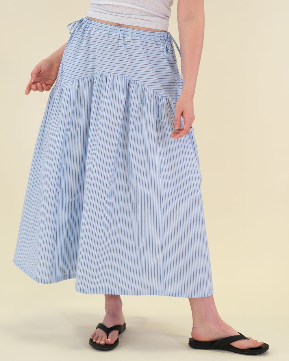 Woman wearing the Sabrina Skirt sewing pattern from BF Patterns on The Fold Line. A skirt pattern made in cotton lawn, batiste, poplin, or lightweight linen or linen blend fabric, featuring an elastic waistband, drawstrings, gently curved yoke, in-seam pockets, and above ankle length.