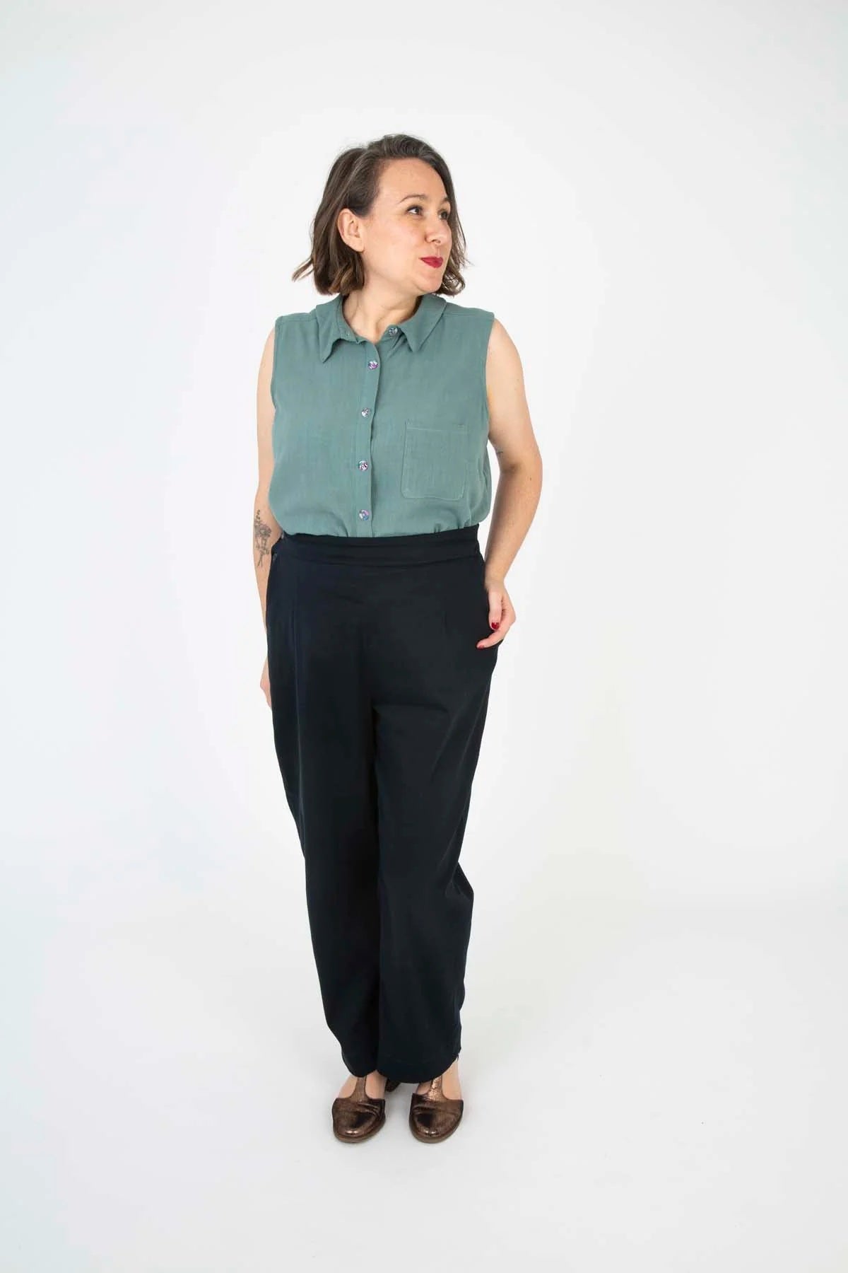 Woman wearing the Sally Shirt sewing pattern from Sew Over It on The Fold Line. A sleeveless shirt pattern made in cotton lawn, poplin, viscose linen, shirting, silk, or viscose fabric, featuring a collar and stand, back yoke with box pleat, button front, and patch pocket.