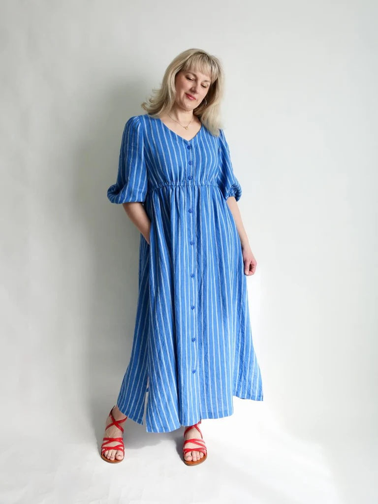 Woman wearing the Sapphire Dress sewing pattern from Made by Rae on The Fold Line. A dress pattern made in linen, cotton lawn, voile, double gauze, poplin, shirting, shot cotton, rayon challis, rayon/viscose blend, or silk noil fabric, featuring a V-neckline, button front, mid-length sleeves, elastic waist, in-seam pockets, side vents, and maxi length.