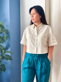 Woman wearing the Seneca Shirt sewing pattern from French Navy on The Fold Line. A shirt pattern made in linen, chambray, cotton, cotton twill, denim, viscose, rayon challis, or cotton blend fabric, featuring a cropped boxy fit, button-up front, two-piece collar, dropped shoulders, and elbow length sleeves.