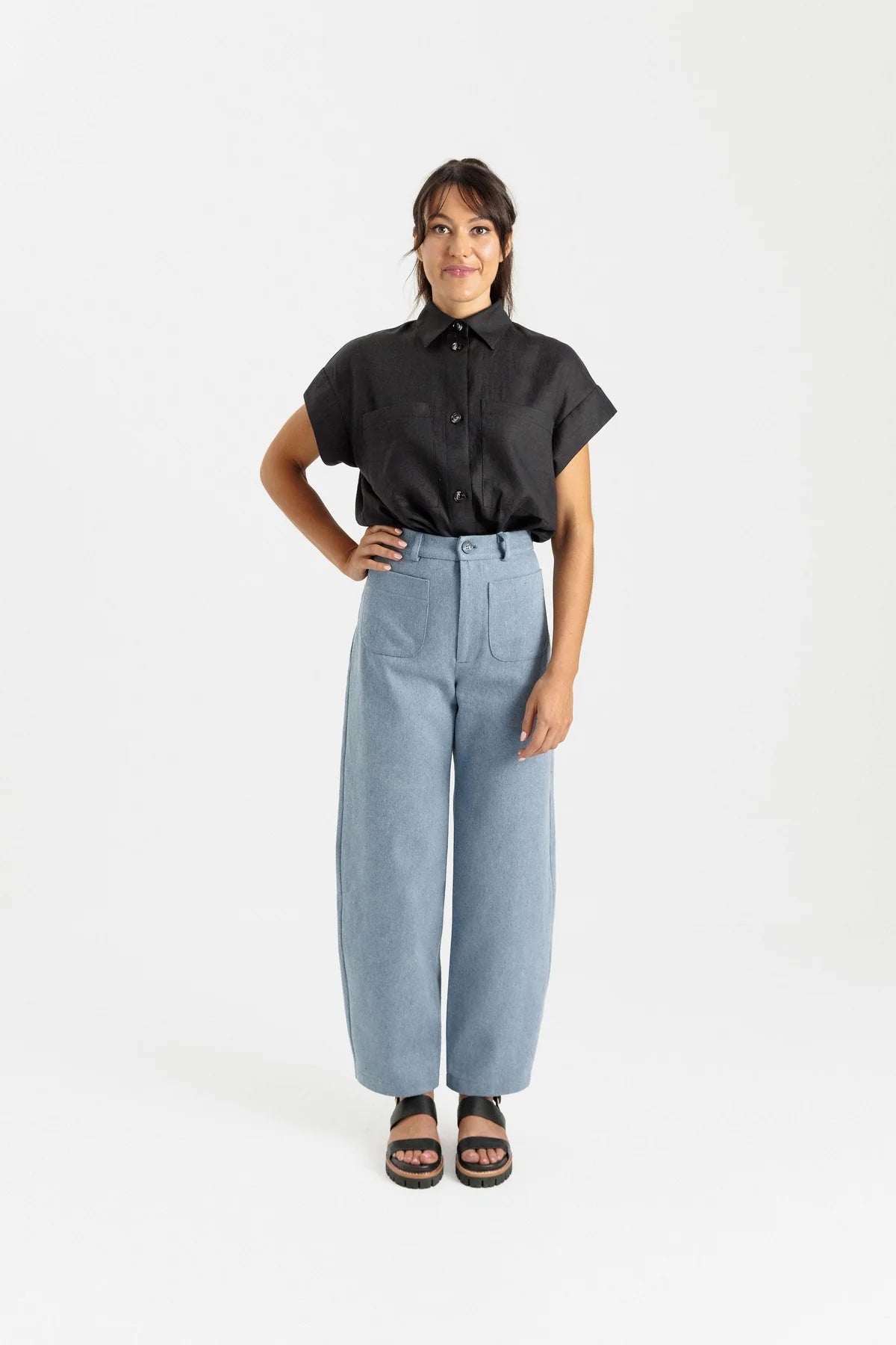 Woman wearing the Sera Pant sewing pattern from Papercut Patterns on The Fold Line. A pants pattern made in cotton drill, denim, canvas, or linen fabric, featuring a high waist, fly front, barrel leg, and rounded front pockets.