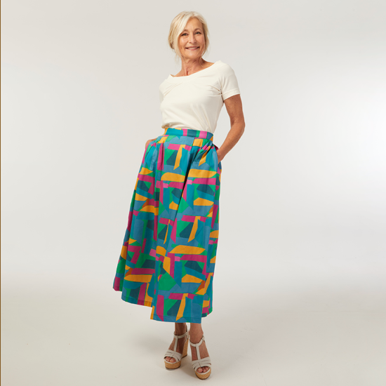 Woman wearing the Servane Skirt sewing pattern from Coralie Bijasson on The Fold Line. A skirt pattern made in Tencel, crepe, gabardine, cotton or linen canvas, double gauze, or viscose poplin fabric, featuring pleats at the front and back, side pockets, an invisible zipper, and midi length.