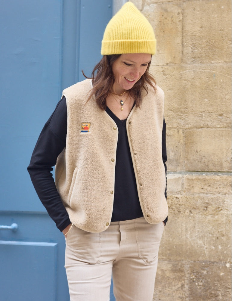 Woman wearing the Sherpa Vest sewing pattern from Atelier Scämmit on The Fold Line. A vest pattern made in wool, jacquard, sweatshirt, or sherpa fabric, featuring a V-neckline, bound edges, welt pockets, and snap button closure.