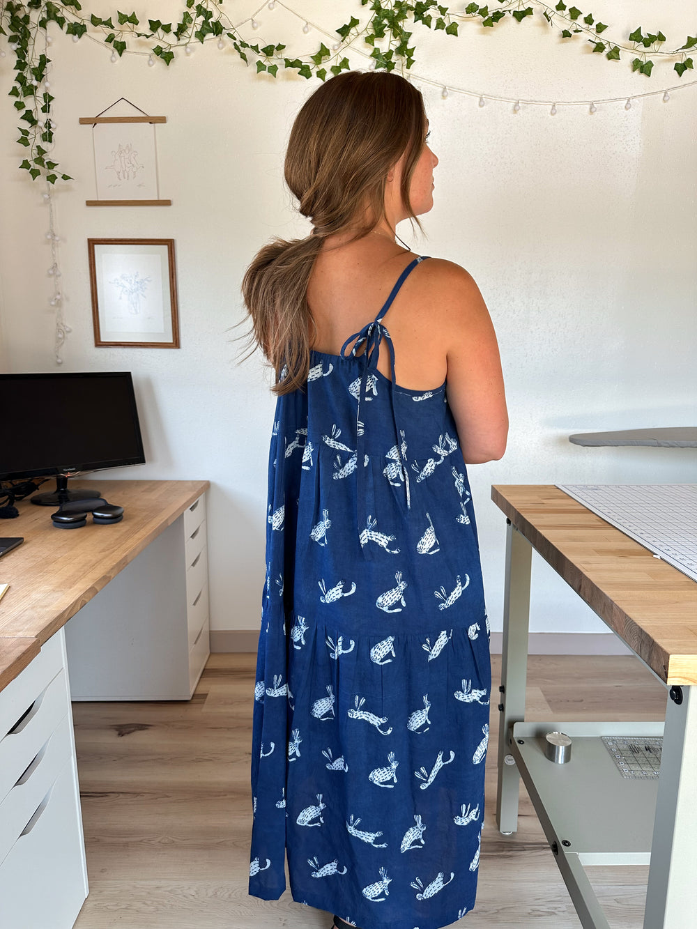 Woman wearing the Skyline Dress sewing pattern from Syd Graham Patterns on The Fold Line. A dress pattern made in cotton or linen fabric, featuring adjustable straps, gathered tiers, and pockets.