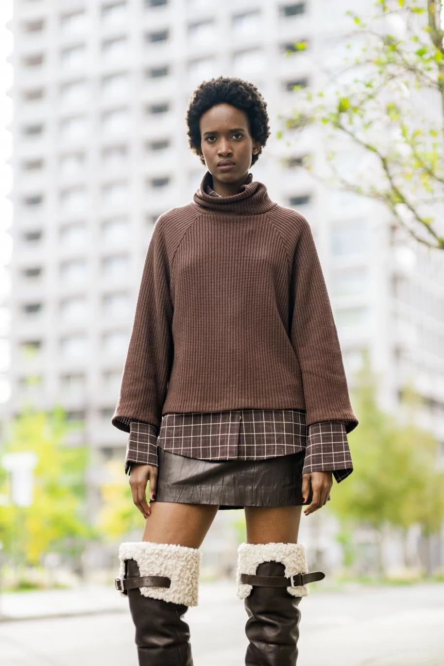 Woman wearing the Sofia Sweater sewing pattern from Fibre Mood on The Fold Line. A jumper pattern made in knit fabric, featuring a relaxed fit, high neck, and wide raglan sleeves. 