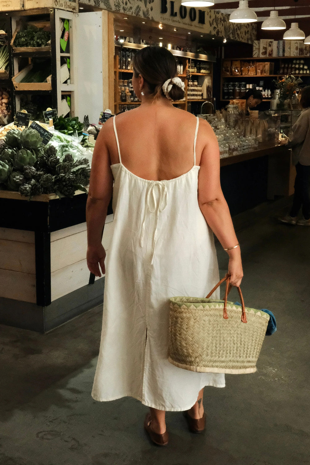 Woman wearing the Solig Dress sewing pattern from Paradise Patterns on The Fold Line. A dress pattern made in cotton, linen, rayon, or tencel fabric, featuring a curved front neckline, side seam bust darts, thin straps, a scooped gathered back with ties, and maxi length. 