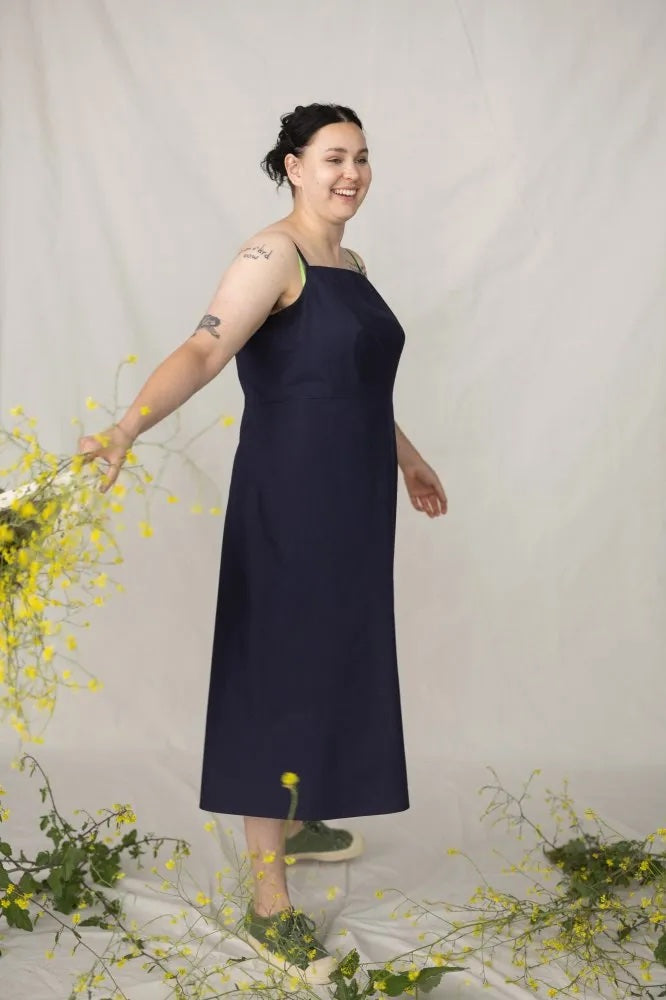 Woman wearing the Sommer Dress sewing pattern from Merchant & Mills on The Fold Line. A dress pattern made in poplin, cotton chambray, dress weight denim, seersucker, cotton lawn, or cotton/linen blend fabric, featuring narrow straps, a horizontal bust dart, concealed side zip, and midi length.