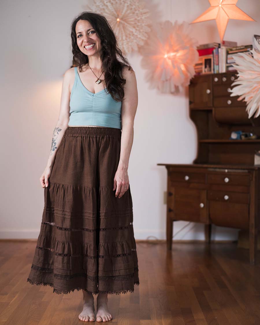 Woman wearing the Songbird Skirt and Tank Top sewing pattern from Sew Liberated on The Fold Line. A top and skirt pattern made in knit fabric for the top and woven fabric for the skirt, featuring a strappy tank top with centre front gathers and a built in shelf bra, and a skirt with an elastic waist, gathered tiers, and deep pockets.