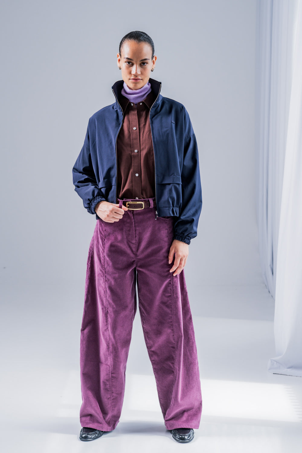 Woman wearing the Sora Trousers sewing pattern from Fibre Mood on The Fold Line. A trousers pattern made in denim, corduroy, velvet, cotton twill, woven jacquard, or leather fabric, featuring a barrel shape, fly front, front leg seam, front jeans pockets, back yoke, and back patch pockets.