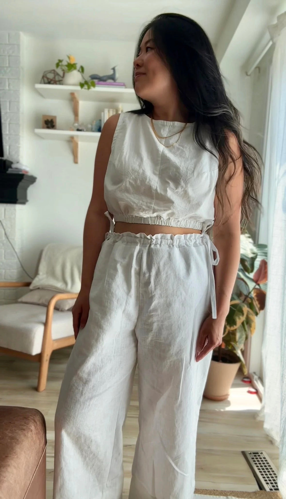 Woman wearing the Sourdough Top sewing pattern from Sew Bake Make on The Fold Line. A sleeveless top pattern made in linen, linen blend, cotton voile, or cotton blend fabric, featuring a boat neckline, crop length, and elasticated hem.
