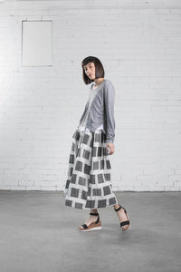Woman wearing the Staley Top sewing pattern from Elbe Textiles on The Fold Line. A top pattern made in knit fabric, featuring a long sleeve top with a scooped neckline and split hem layered over a short sleeve T-shirt with a scooped neckline and curved hem.