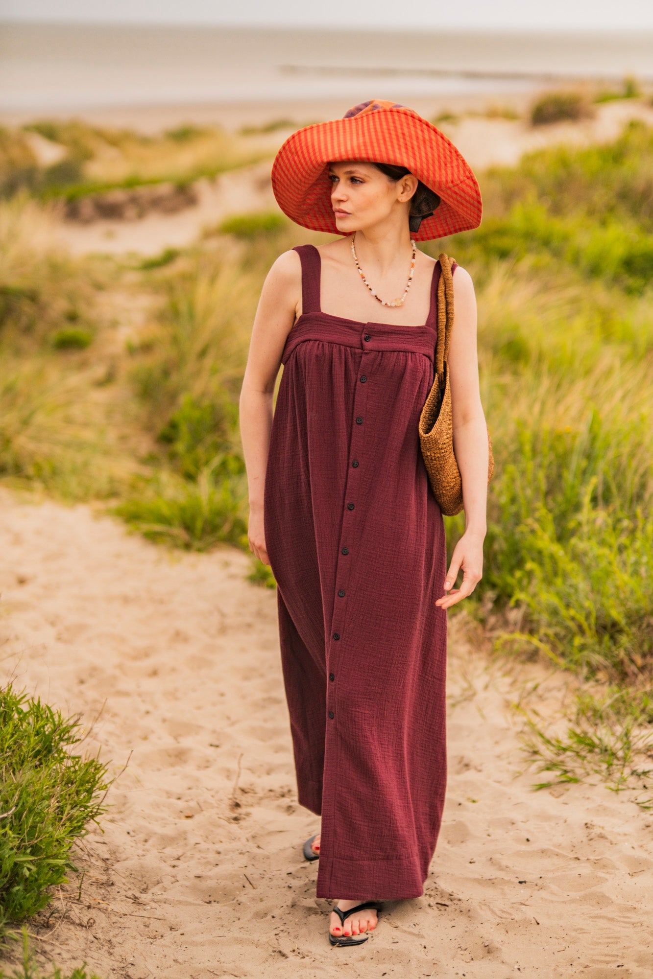 Woman wearing the Storm Dress sewing pattern from Fibre Mood on The Fold Line. A dress pattern made in broderie, poplin, chambray, lyocell, double gauze, organza, seersucker, or linen fabric, featuring wide shoulder straps, a square neckline, gathers, button front, side seam pockets, and maxi length.
