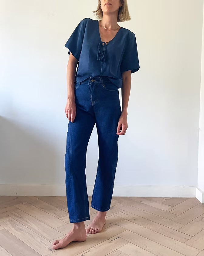 Woman wearing the Stratus Top sewing pattern from French Navy on The Fold Line. A top pattern made in viscose, cotton, chambray, linen, or linen/viscose blend fabric, featuring a relaxed fit, low V-neckline with a tie, and short set-in sleeves.