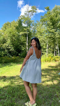 Woman wearing the Sundae Sundress sewing pattern from Sew Bake Make on The Fold Line. A strappy tent dress pattern made in linen, linen blend, cotton voile, cotton lawn, cotton shirting, double gauze, or cotton blend fabric, featuring a subtle sweetheart neckline, adjustable tie straps, optional waist ties, low gathered back, wide hem facing, and mini length.