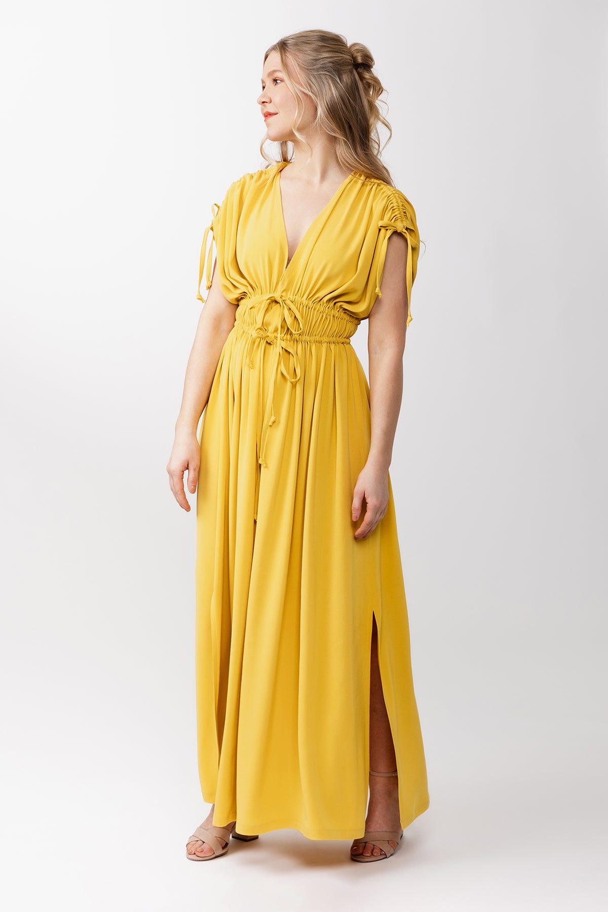 Woman wearing the Suvi Caftan Maxi Dress sewing pattern from Named on The Fold Line. A dress pattern made in double gauze, cotton lawn, washed linen, viscose challis, crepe, or satin fabric, featuring a deep V-neck, gathered shoulders, two waist cords, side slits, and maxi length.