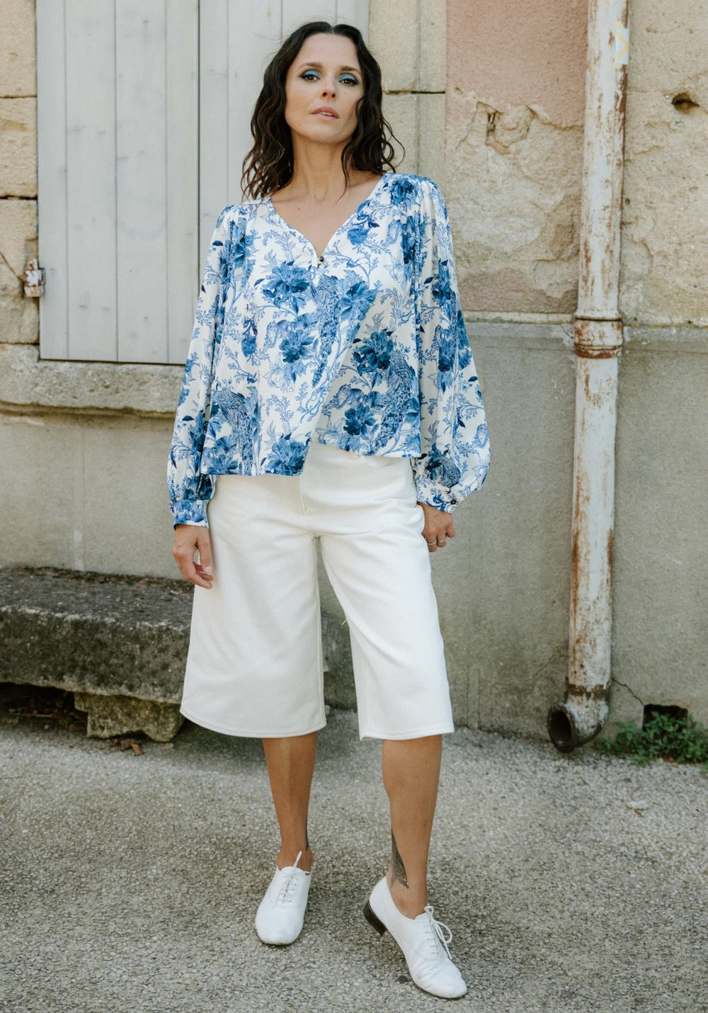 Woman wearing the Synopsis Bermuda Shorts sewing pattern from Maison Fauve on The Fold Line. A shorts pattern made in denim, cotton gabardine, medium weight cotton twill, corduroy, or faux suede fabric, featuring a relaxed fit, low-rise waist, wide leg, and below-the-knee length.