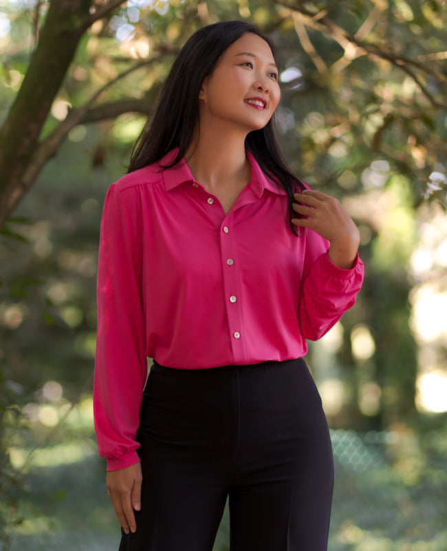 Woman wearing the Talavera Blouse sewing pattern from Itch to Stitch on The Fold Line. A shirt pattern made in lightweight knit fabric, featuring a classic shirt collar, curved front and back yokes with soft gathers, front button closure, and long sleeves with cuffs.