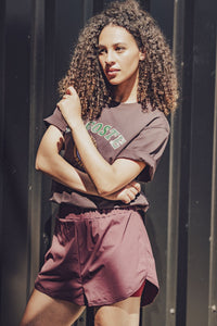 Woman wearing the Tavio Shorts sewing pattern from Fibre Mood on The Fold Line. A sports shorts pattern made in microfibre, nylon taslan, modal, or polyester ripstop fabric, featuring a relaxed fit, elastic waist, and built-in pants.