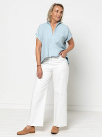 Woman wearing the Teddy Designer Top sewing pattern from Style Arc on The Fold Line. A top pattern made in linen, silk, or crepe fabric, featuring a collar, grown-on short sleeves with folded cuffs, a wide hem facing, and high-low hemline.